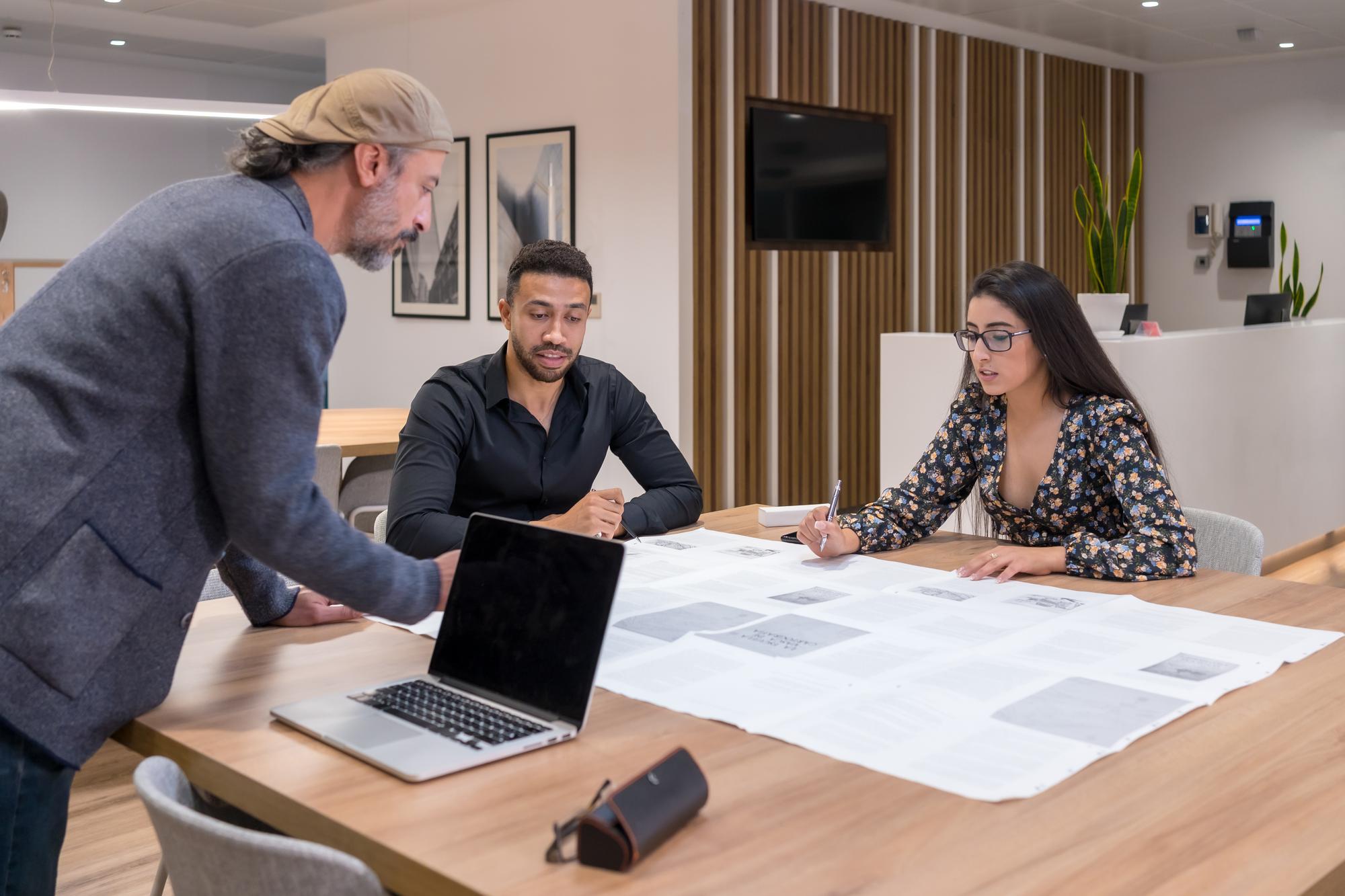 Agent imobiliar consultând proprietarul lângă planuri