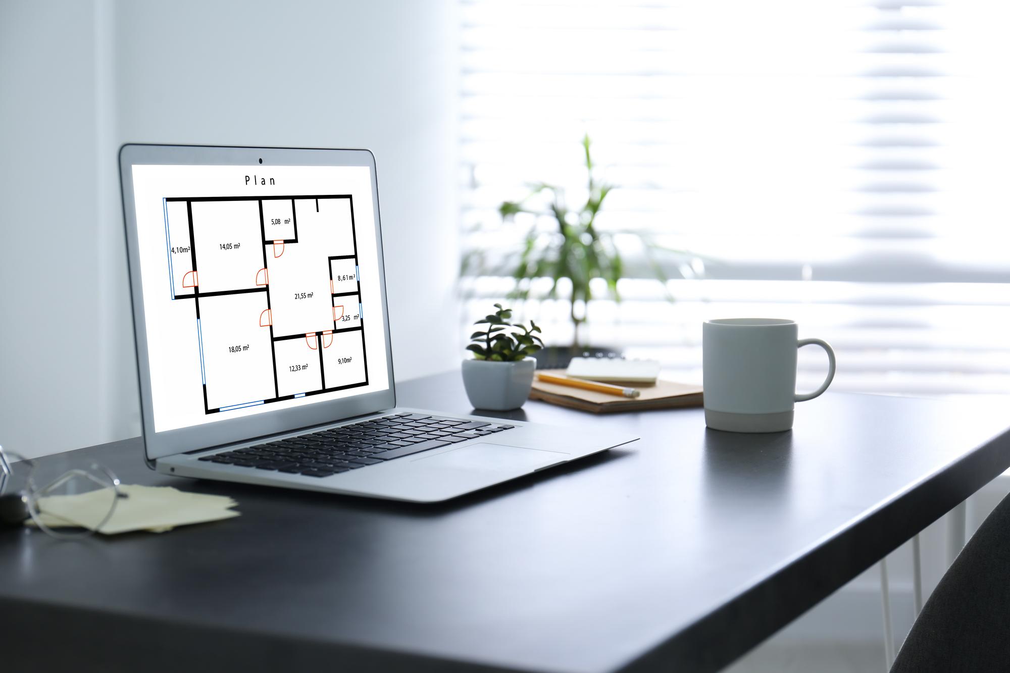 Birou imobiliar cu planuri și laptop